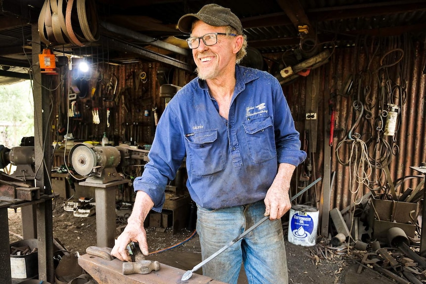 a man holds a piece of metal, smiling