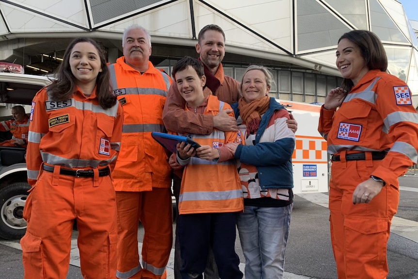 Three SES crew members in orange suits smile alongside the Callaghan family