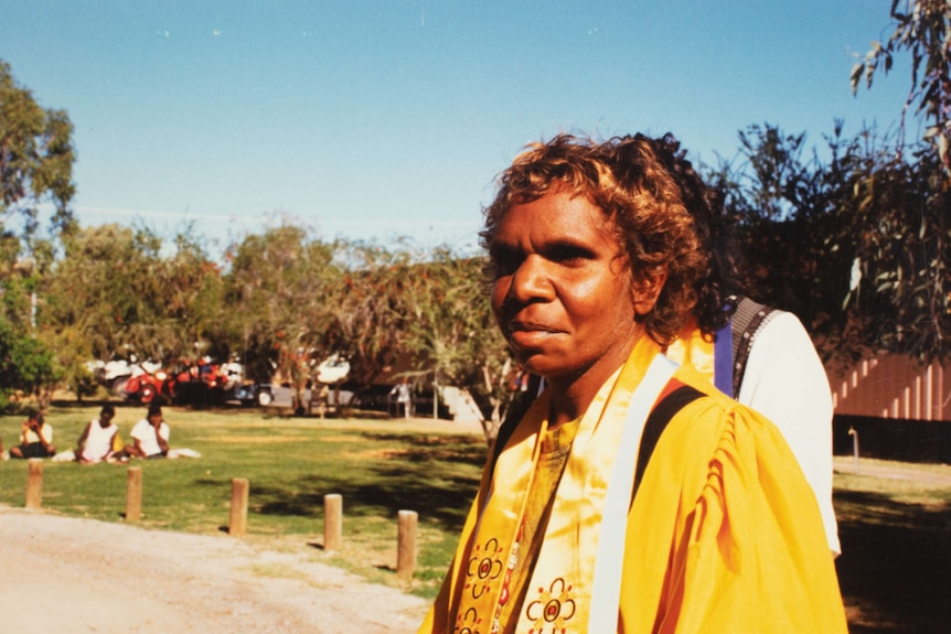 An old photo of an Aboriginal woman wearing a yellow graduation gown