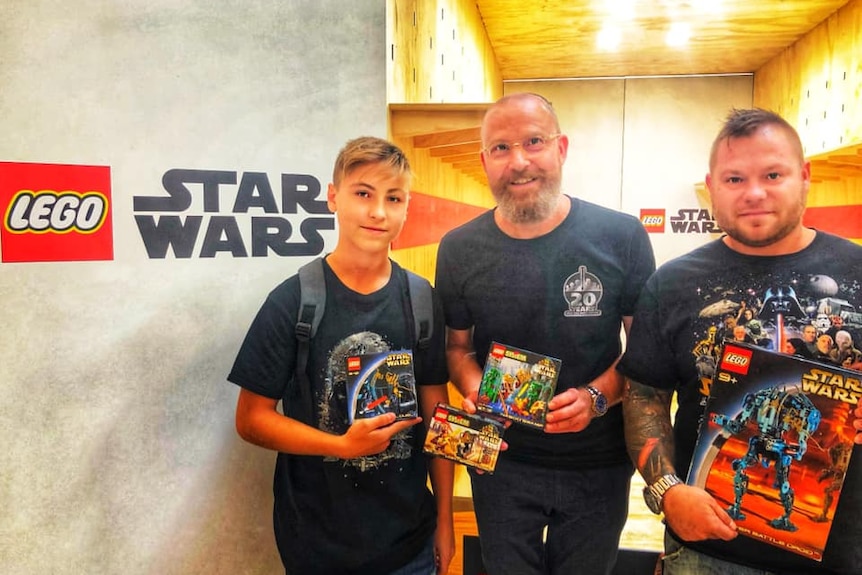 Two men and a boy at some kind of Star Wars Lego event.