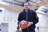 A tall man holding a basketball.