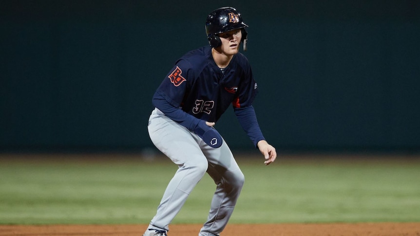 A male Australian baseball player stands between the bases while playing for Bowling Green Hot Rods in the United States.