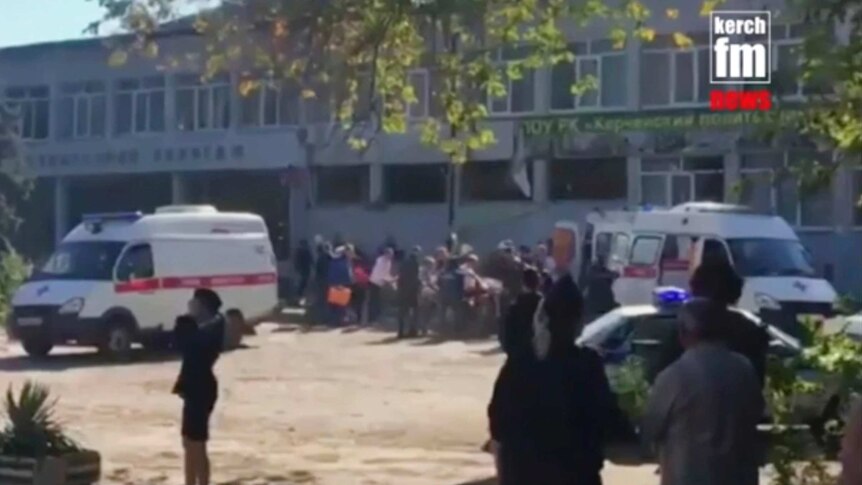 In this image made from video, emergency services load an injured person into an ambulance outside the college.