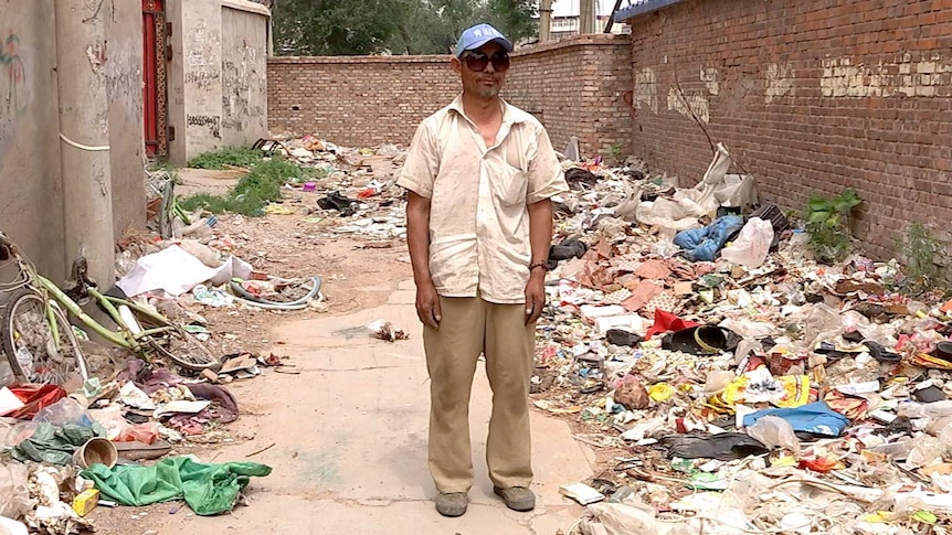 Wang Jindong standing near the rubbish.