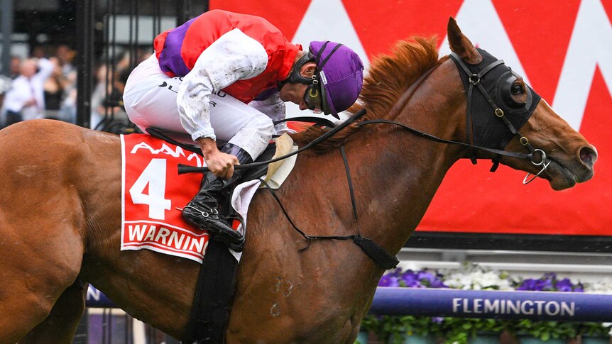 A jockey bows his head as he rides his horse past the winning post to take out the Victoria Derby.