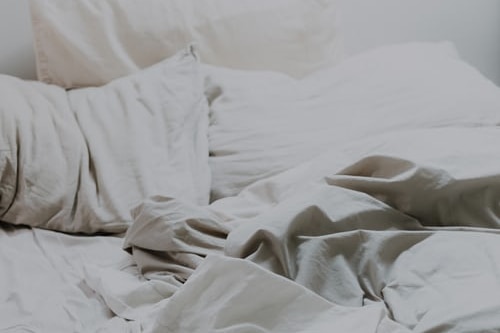 A bed with messy sheets and pillows