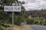 A sign for a village called Sallys Flat with the handwritten word chested underneath