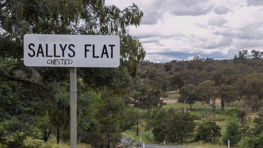 A sign for a village called Sallys Flat with the handwritten word chested underneath