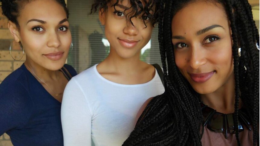 Three sisters smiling at camera while taking a selfie.