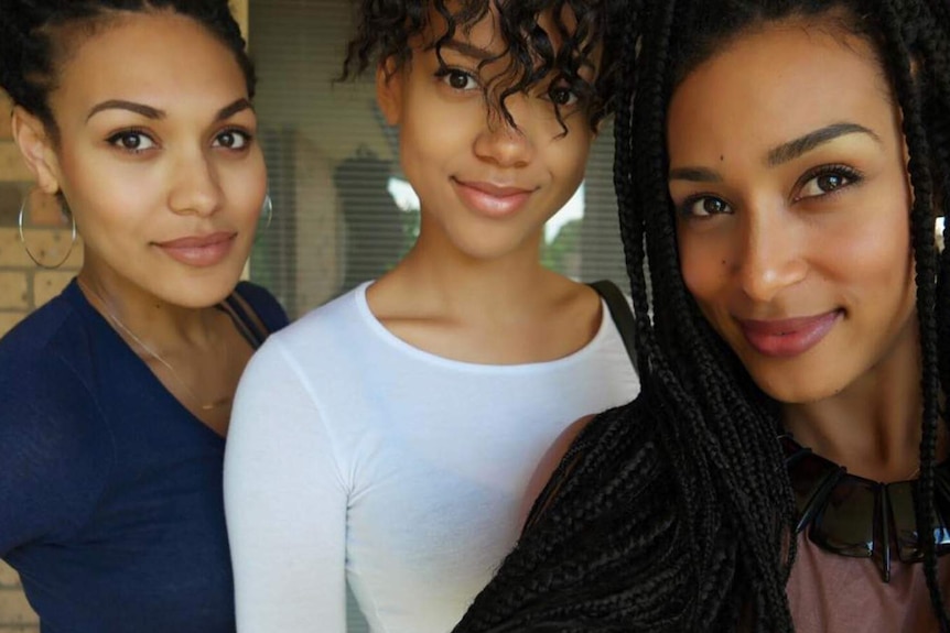 Three sisters smiling at camera while taking a selfie.