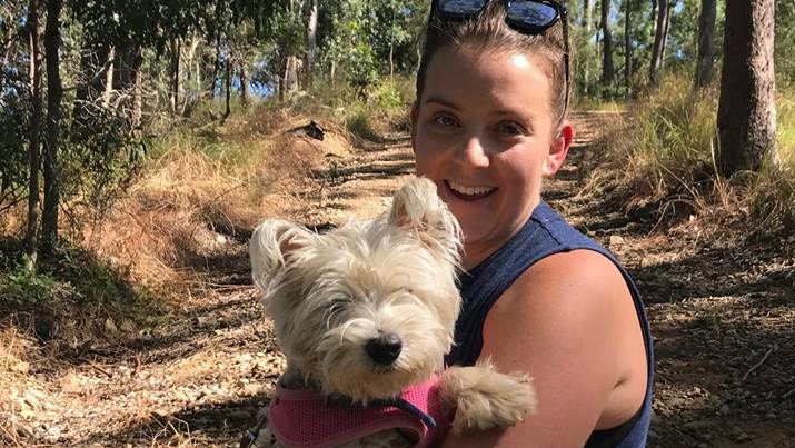 A woman holding Dickie the dog in bushland