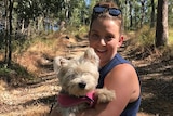 A woman holding Dickie the dog in bushland