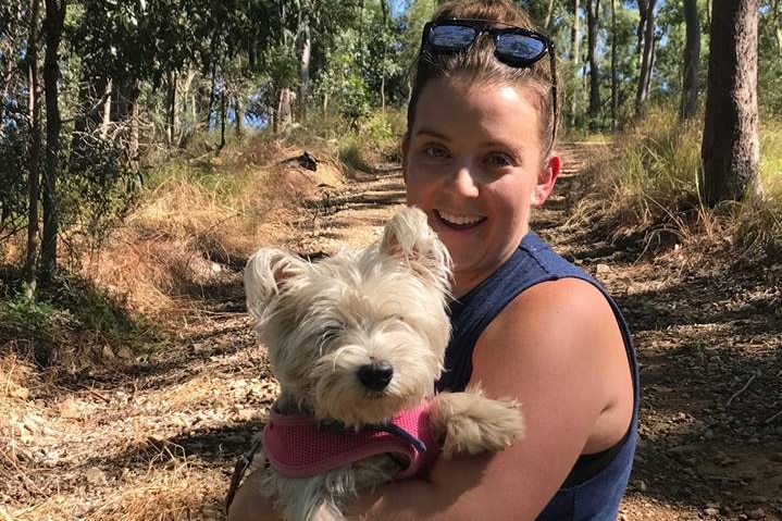 A woman holding Dickie the dog in bushland