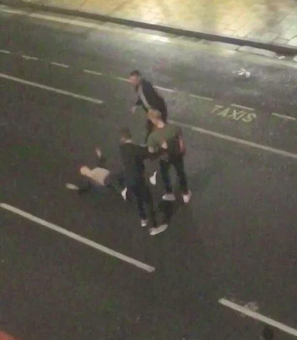 CCTV footage filmed from above shows a man lying on the street surrounded by three other men.