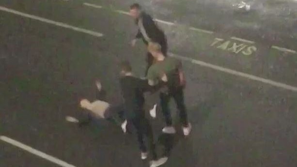 CCTV footage filmed from above shows a man lying on the street surrounded by three other men.
