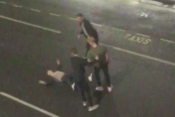 CCTV footage filmed from above shows a man lying on the street surrounded by three other men.