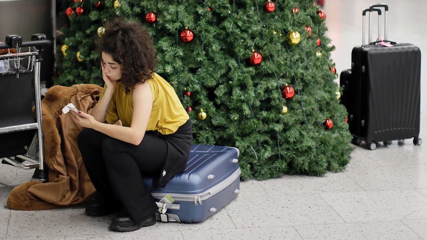 Le passager attend à côté d'un arbre de Noël