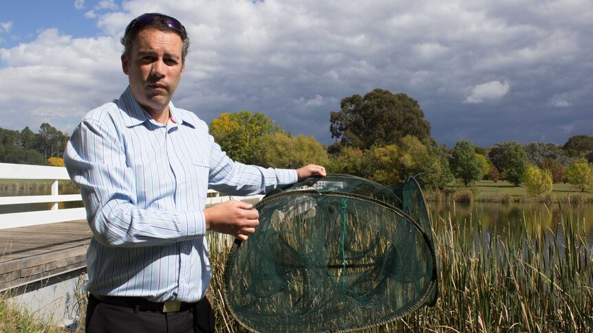 ACT Parks and Conservation director Daniel Iglesias holding a trap pulled from Lake Burley Griffin