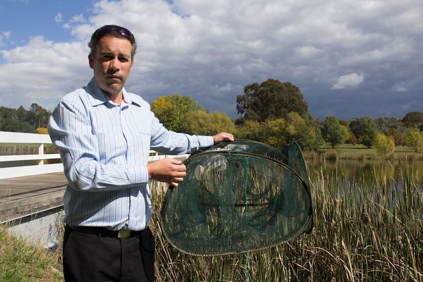 ACT Parks and Conservation director Daniel Iglesias holding a trap pulled from Lake Burley Griffin