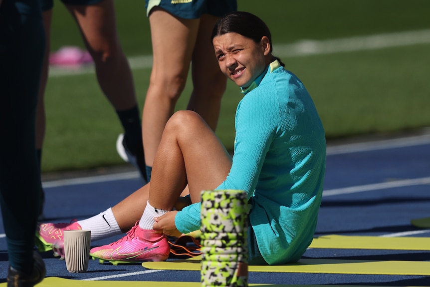 Sam Kerr is pictured at the Matildas' training session in Brisbane. She is sitting on the track with a foam roller