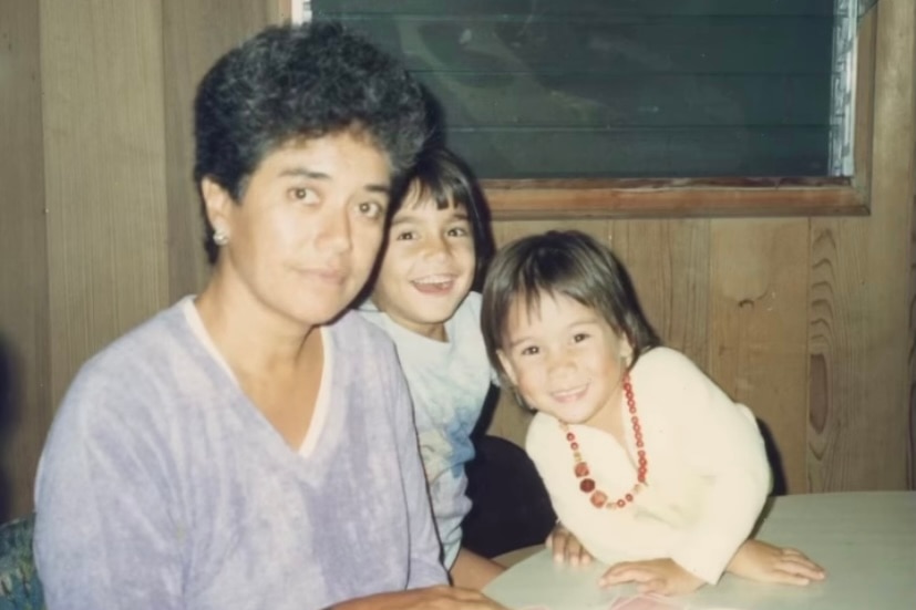 A woman at a table with two smiling children. 