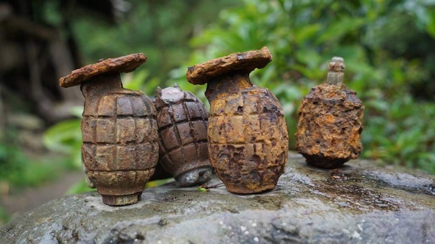 Four rusted grenades on a rock