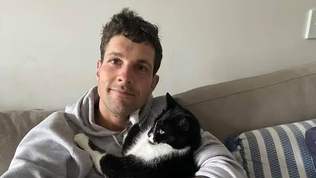 a man smiling holding a cat