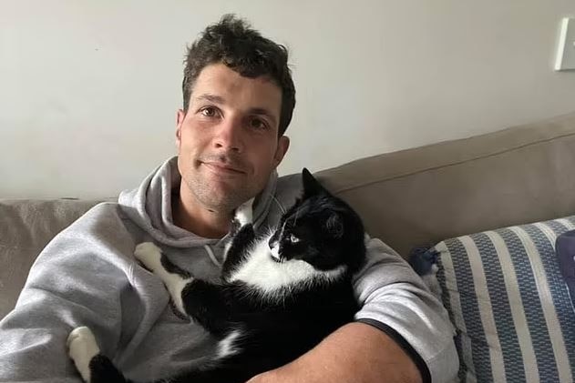 a man smiling holding a cat