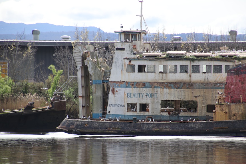 Close up of rusty ferry and tug boat docked on river.
