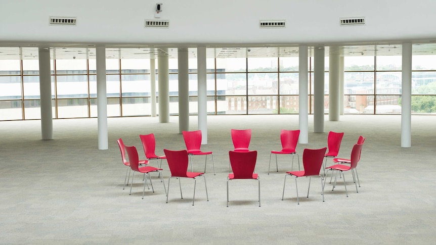Red chairs in a circle in a large room.
