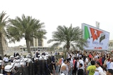 Anti-government protesters shout slogans at riot policemen as they block a road in Manama