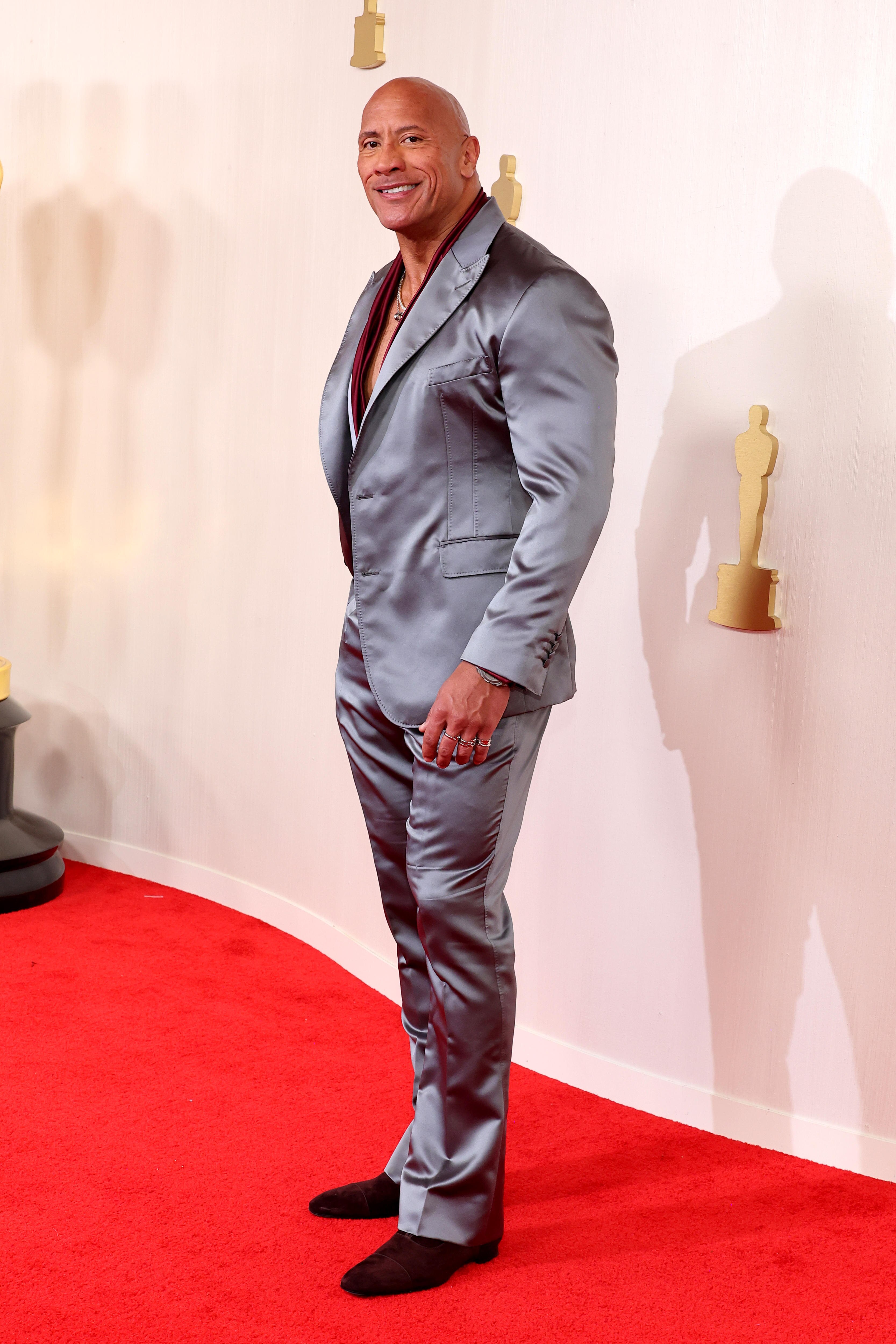 Dwayne Johnson con traje plateado en la alfombra roja de los Oscar