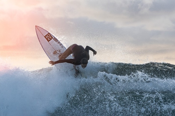 A female surfer carves a wave at sunset.