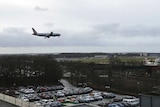 A plane flying over the Gatwick airport and a carpark.