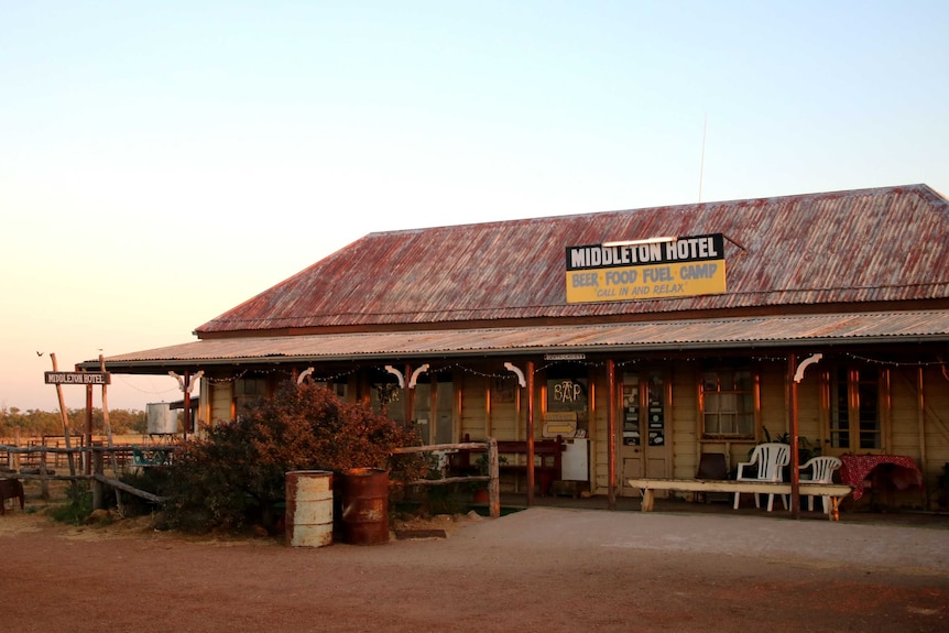 An old, slightly run down pub with a rusty red iron roof and a sign that reads "Middleton Hotel, Beer food, fuel, camp"