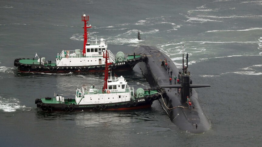 Submarine with two other vessels attached in the ocean.