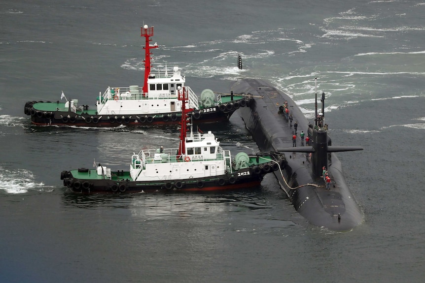 Submarine with two other vessels attached in the ocean.