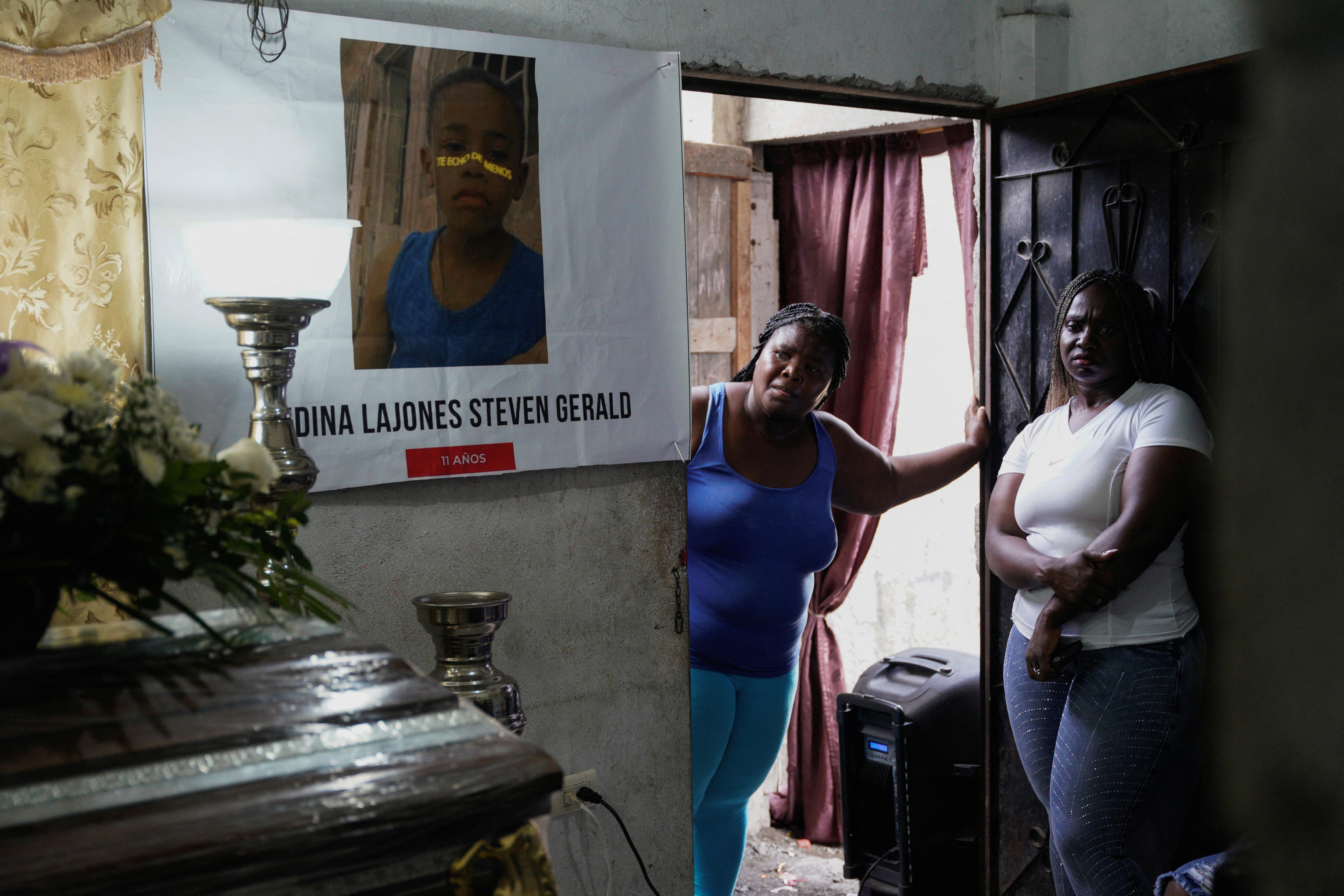 Duas mulheres estão em uma porta olhando para um caixão. 