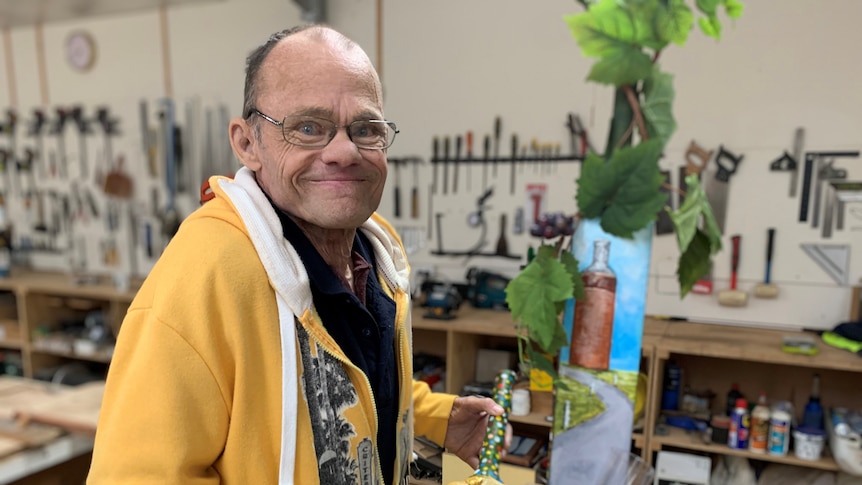  Brett Wilthshire holds up a cricket painted cricket bat featuring bent nail figurines.