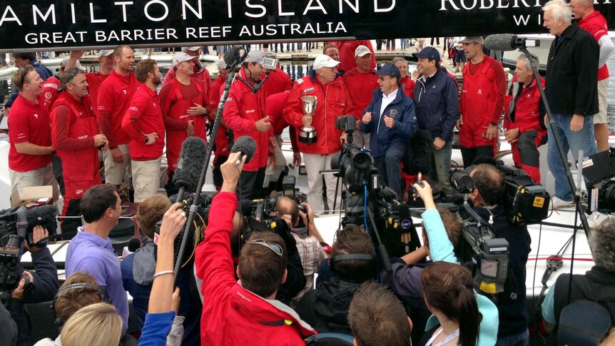 Wild Oats XI owner Bob Oatley holds the cup and is surrounded by the yacht's crew.