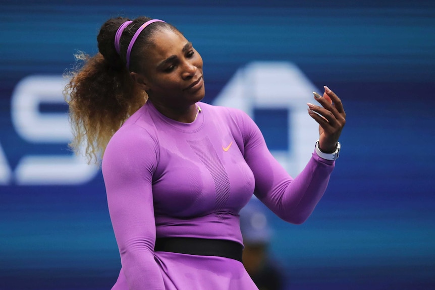 Serena Williams holds her hand up and closes her eyes with a tilt of her head.