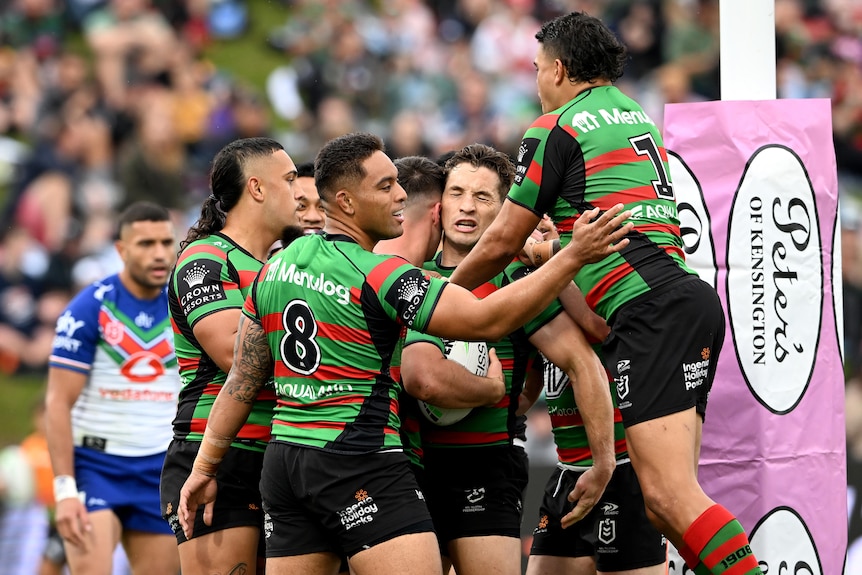 Rabbitohs players surround and jump on Lachlan Ilias near the goalposts