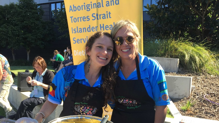 Photo of two women in front of pot of soup