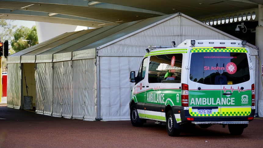 An ambulance parked in front of a white marquee