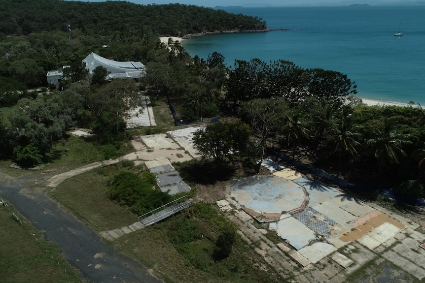 Drone shot of old concrete slabs among greenery back from the beach on an island