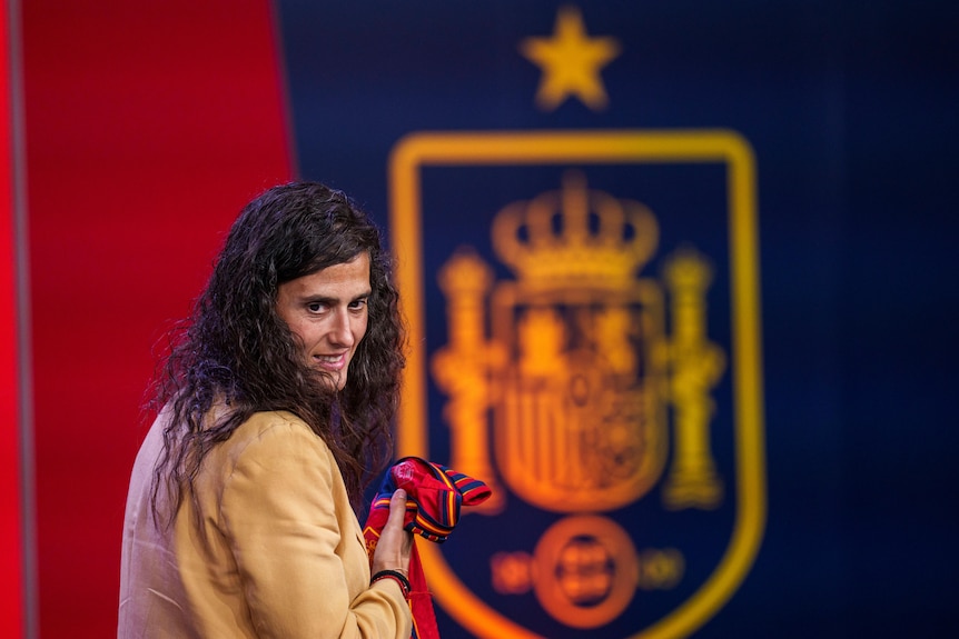 Montse Tome turns her face towards the camera, holding a Spain football jersey in her hand