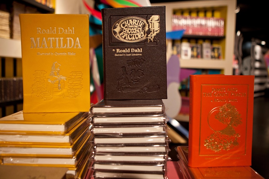 Three books on display. They are yellow, brown and red. 