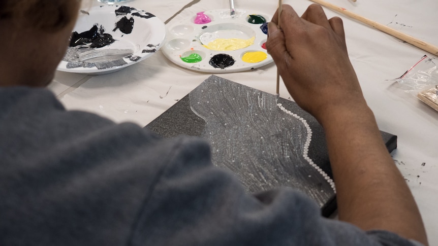 An AWP inmate dot-paints as part of a NAIDOC Week program.