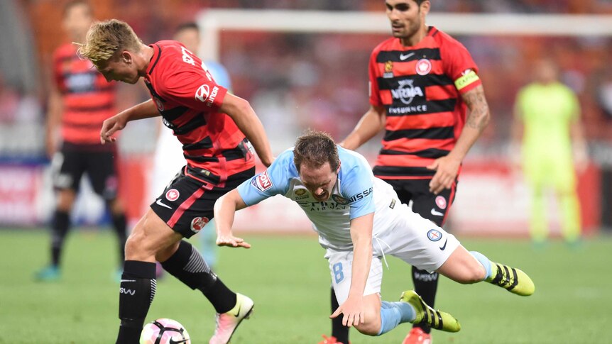 Neil Kilkenny of Melbourne City falls to the ground as he is tackled by Lachlan Scott of the Wanderers.