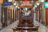 A barista waits in his coffee stand for customers in an empty Adelaide Arcade.